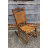 An Edwardian polished as walnut cane seat and back rocking chair