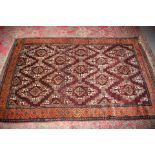 A Kazak style rug with thirteen diamond lozenges on a plum ground on single boarder in shades of