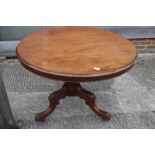 A 19th century circular tilt top dining table, on carved column and tripod splay castored support,