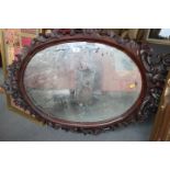 A carved hardwood framed oval wall mirror, 44" x 27" overall