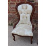 A mahogany showframe low seat nursing chair, button upholstered in a floral fabric, on cabriole