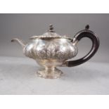 A bachelor's Georgian silver teapot with embossed floral decoration and ebonised handle, 11.8oz troy