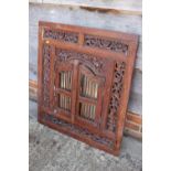 An Indian carved and pierced framed wall mirror enclosed two spindle doors, 36" x 32"