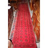 A Bokhara runner with fifty-two guls on a red ground, 146" x 31" approx