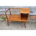 A 1960s teak spindle back telephone seat, on splay supports, 34" wide x 17" deep x 28" high