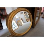 An oval gilt framed wall mirror with bevelled plate, 24" x 29" overall