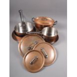 Three copper and iron handled saucepans, two similar frying pans, a tureen and a hanging rack