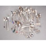 An assortment of silver flatware, including pastry forks, souvenir spoons, teaspoons, a caddy