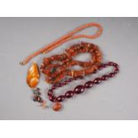 An amber pebble necklace, 37.6g, a coral necklace and two earrings, a cherry "amber" necklace, an