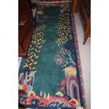A 1930s style Chinese contour pile rug with stylised bamboo, rocks and prunus tree design on a green