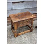 A carved oak box seat stool of 17th century design, on turned and stretchered supports, 20" wide x