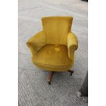 A 1930s revolving office chair, upholstered in an old gold fabric, on castored supports