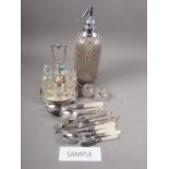 A selection of silver plated cutlery, a cut glass and plated cruet on stand, a soda syphon and other