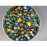 A biscuit tin containing a collection of glass marbles