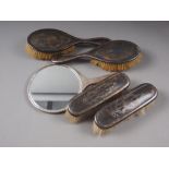 Four matching silver mounted and tortoiseshell-backed dressing table brushes and a silver-backed