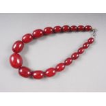 An Art Deco cherry amber Bakelite graduated bead necklace, the largest oval bead 20mm wide, total