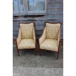 A pair of Edwardian mahogany and line inlaid armchairs, upholstered in a cream and gold brocade