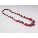An Art Deco cherry amber Bakelite graduated bead necklace, the largest oval bead 22mm wide, total