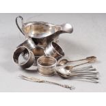 A set of six silver coffee spoons, five silver napkin rings, a white metal pickle fork, a pair of