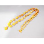 An Art Deco butterscotch/egg yolk graduated bead necklace with silver gilt mounted tear drop-