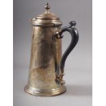 A silver hot water jug of plain design with ebonised handle, on circular stepped base, 8" high, 11.8