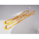 An Art Deco butterscotch/egg yolk graduated bead necklace, the largest oval bead 11mm wide, and