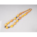 An Art Deco butterscotch/egg yolk amber necklace with white metal and horn spacers, the largest