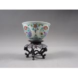 A Chinese Wucai porcelain tea bowl with six-character mark to base, 2 3/4" dia, on hardwood stand