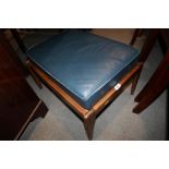 A 1950s walnut stool with leather loose seat cushions, on splay supports, 25" wide x 18" deep x