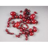 A number of loose Art Deco cherry amber Bakelite beads, the largest 21mm wide, total weight 132.1g