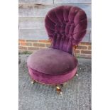 A 19th century mahogany low seat chair with button upholstered back, on turned and castored supports