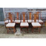 A set of eight Chinese hardwood splat back dining chairs with panel seats and loose cushions, on