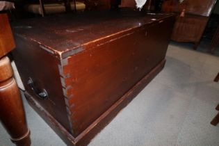 A waxed pine blanket box with black japanned carry handles, on block base and wooden castors, 46"