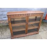 A carved oak bookcase enclosed two glazed doors, on bracket feet, 47" wide x 10 1/2" deep x 38" high