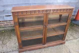 A carved oak bookcase enclosed two glazed doors, on bracket feet, 47" wide x 10 1/2" deep x 38" high