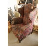 A wing armchair of Georgian design in a Jacquard pattern fabric, on cabriole stretchered supports