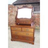 An early 20th century walnut dressing chest, fitted shaped mirror over two jewel drawers and two