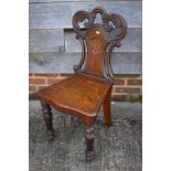 A 19th century carved oak hall chair with panel seat, on shaped supports