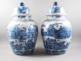 A pair of Chinese blue and white landscape decorated oviform jars and covers, 25" high