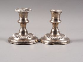 A pair of filled silver squat candlesticks with fluted decoration, on circular bases