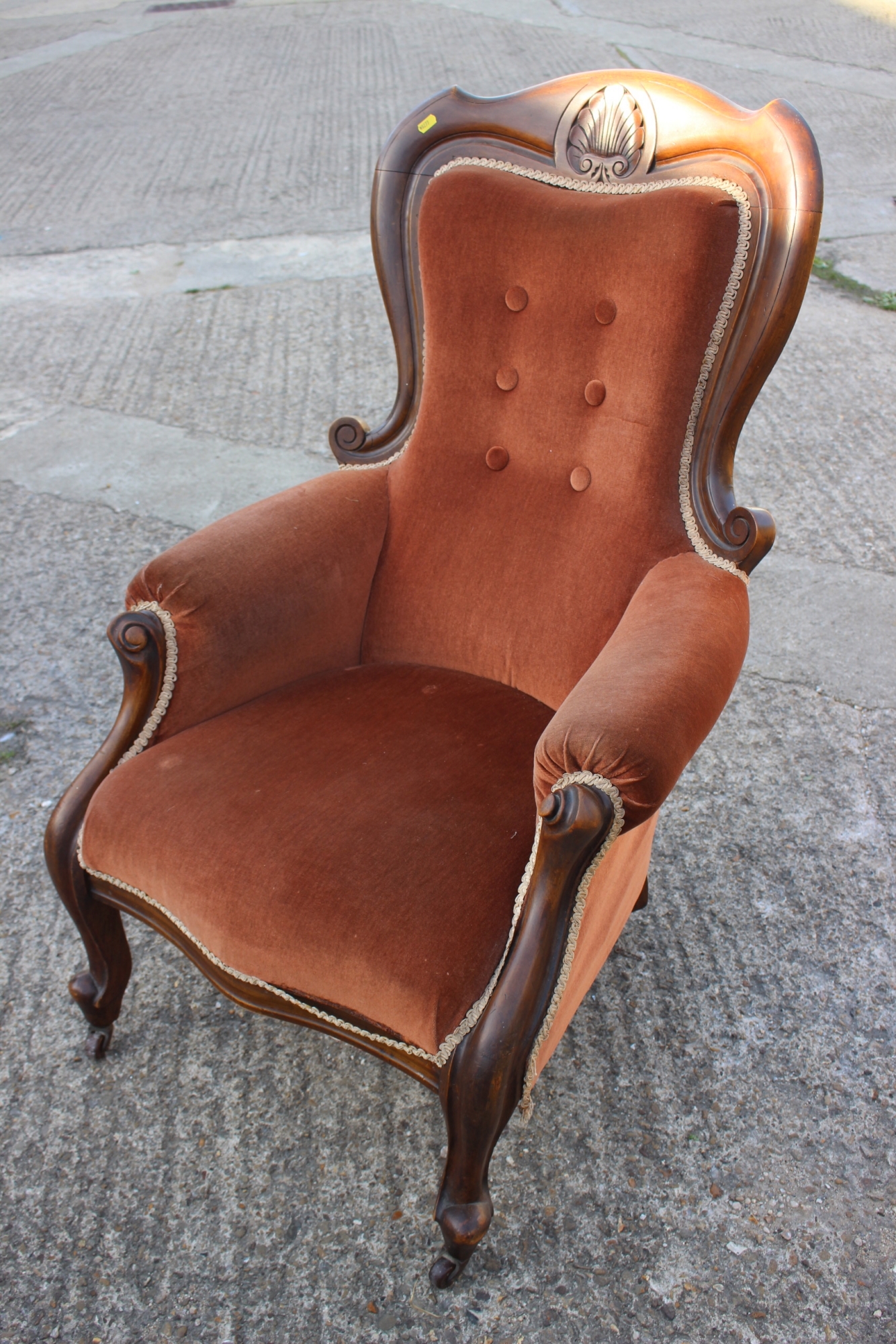 A Victorian carved walnut showframe armchair, upholstered in a rust velour, on cabriole supports
