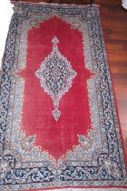 A Persian city rug with scroll design on a red ground and multi-borders, in shades of black, cream