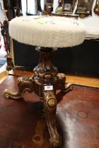 An early 20th century carved walnut circular seat piano stool, on tripod splay support (adjustable