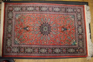 A Kashan/Qum silk wall hanging with central medallion and two lanterns on a red ground and multi-