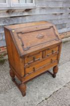 An oak fall front bureau with fitted interior over two long drawers, on turned and stretchered