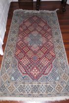 A Persian city rug with central star medallion on a red ground with multiple floral patterns and