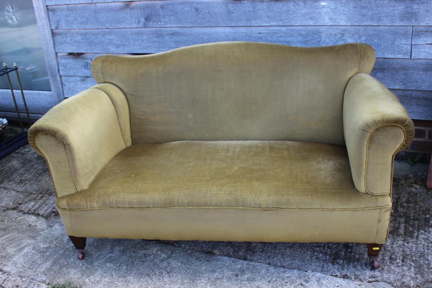 A late 19th century drop-end settee, upholstered in green velour, on square tapered castored