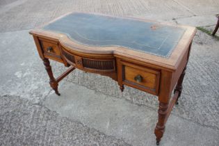 A late 19th century oak break bowfront desk with tooled leather top over three drawers, on turned