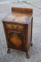 A 1930s figured walnut ledge back bedside cupboard, fitted one drawer, on claw and ball shaped
