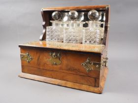 A burr walnut and brass mounted three decanter Tantalus with carry handles and lift over flaps, over